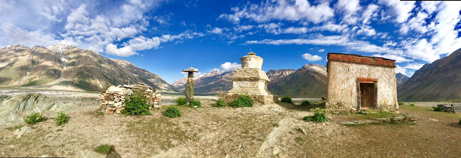Stupa und Steinhütte vor Bergpanorama